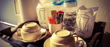 A tray with two cups of coffee, a glass of water, a coffee maker, and a bag of coffee creamer.