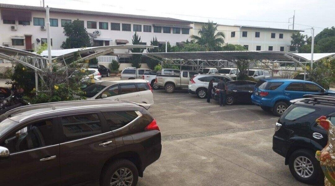 Un parking avec plusieurs voitures, un immeuble à étages et une galerie couverte.