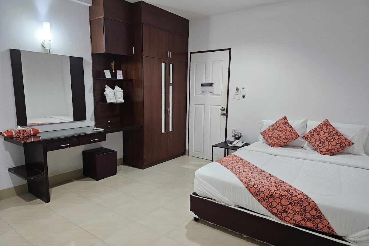 A hotel room with a bed, a desk, a wardrobe, and a mirror.