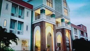 Un edificio de varios pisos con una torre central destacada, ventanas amplias y un balcón.
