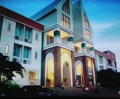 A multi-story building with a prominent central tower, large windows, and a balcony.