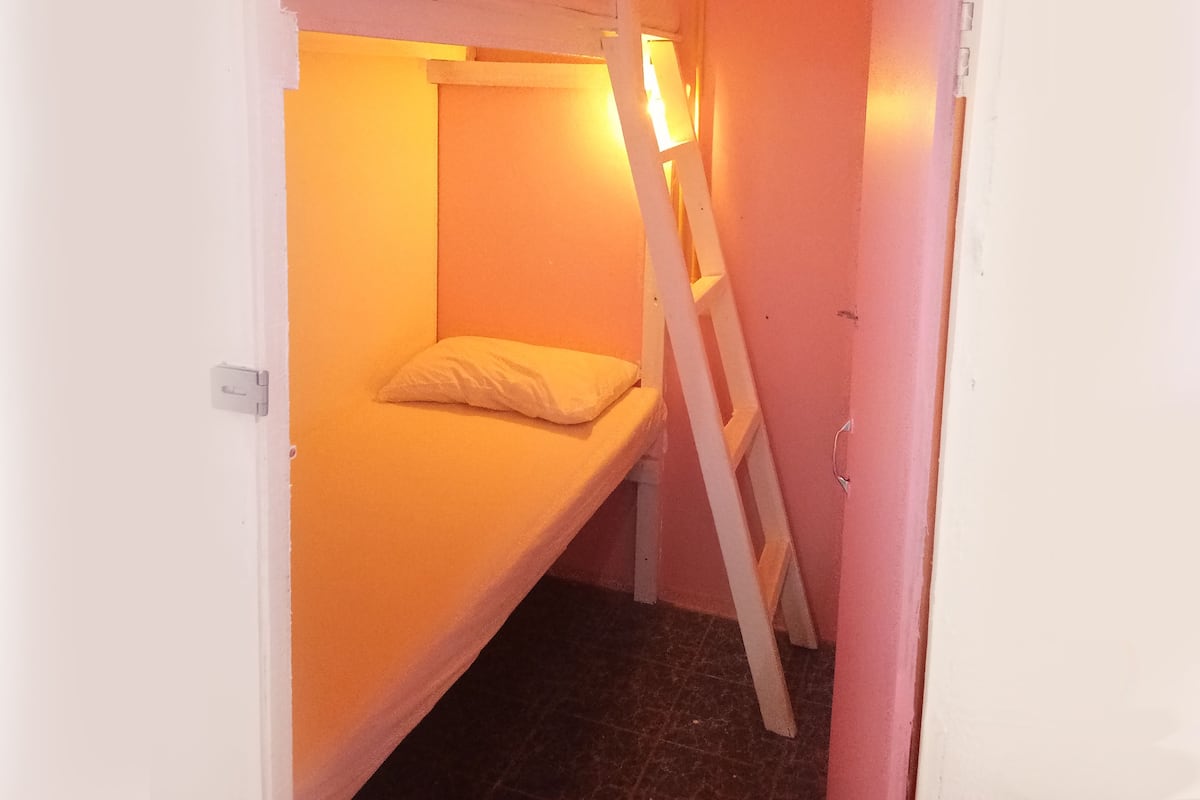 A narrow room with bunk beds and a ladder.