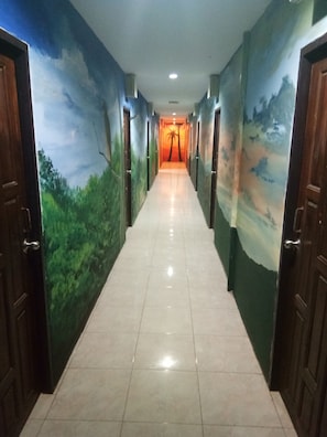A hallway with a mural of a landscape on the walls, leading to a room with a sunset view. - Wild & Wandering Backpacker & Bar (Ko Pha-ngan)