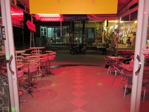 A closed tattoo shop with a red neon sign, a motorcycle parked outside, and a red carpeted floor. - Wild & Wandering Backpacker & Bar (Ko Pha-ngan)