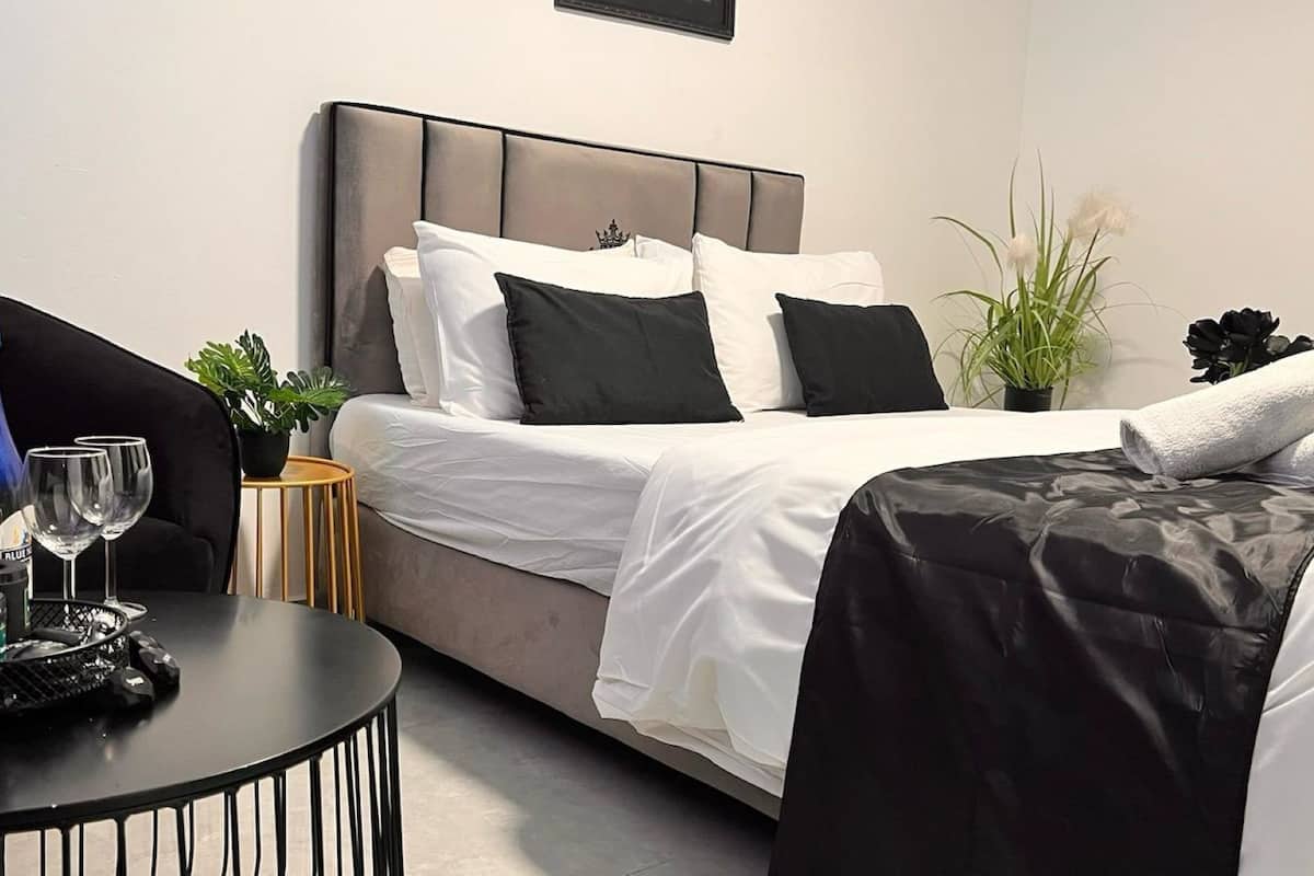 A hotel room with a bed, bedside table, and a potted plant.