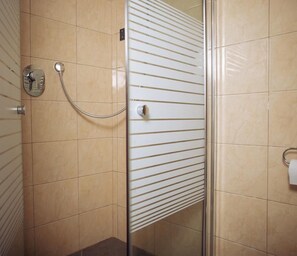 A shower area with beige tiles, a glass door, and a towel rack. - Elis Boutique Hotel (Bat Yam)