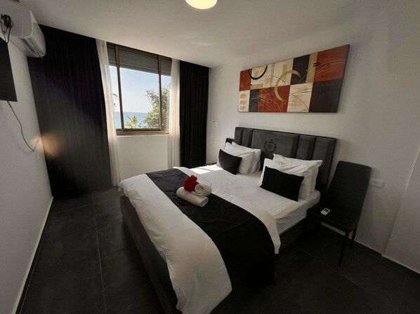 A modern hotel room with a large bed, a view of the outdoors, and a painting on the wall. - Elis Boutique Hotel (Bat Yam)