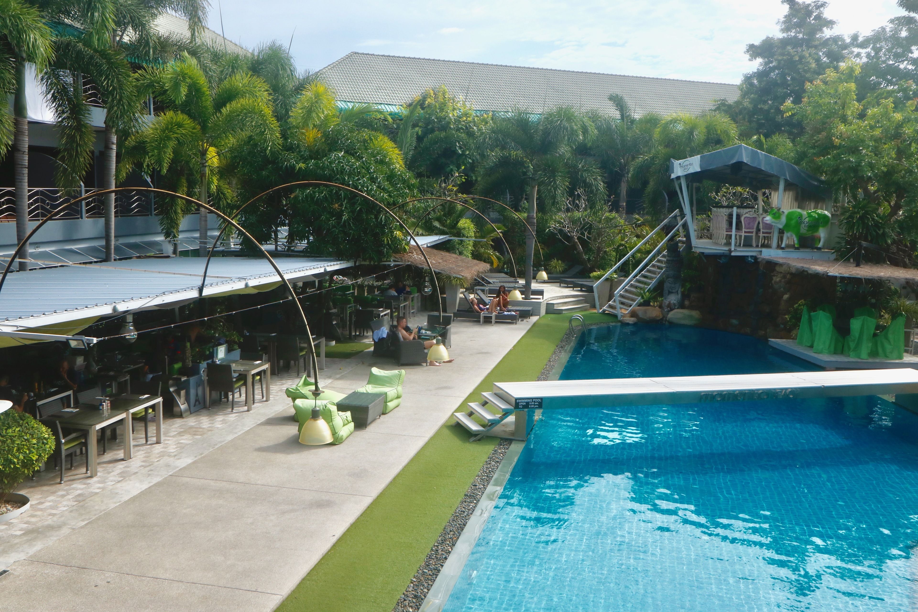 Un espace piscine doté d’une plateforme de plongeon, de chaises longues et de coins salon extérieurs.