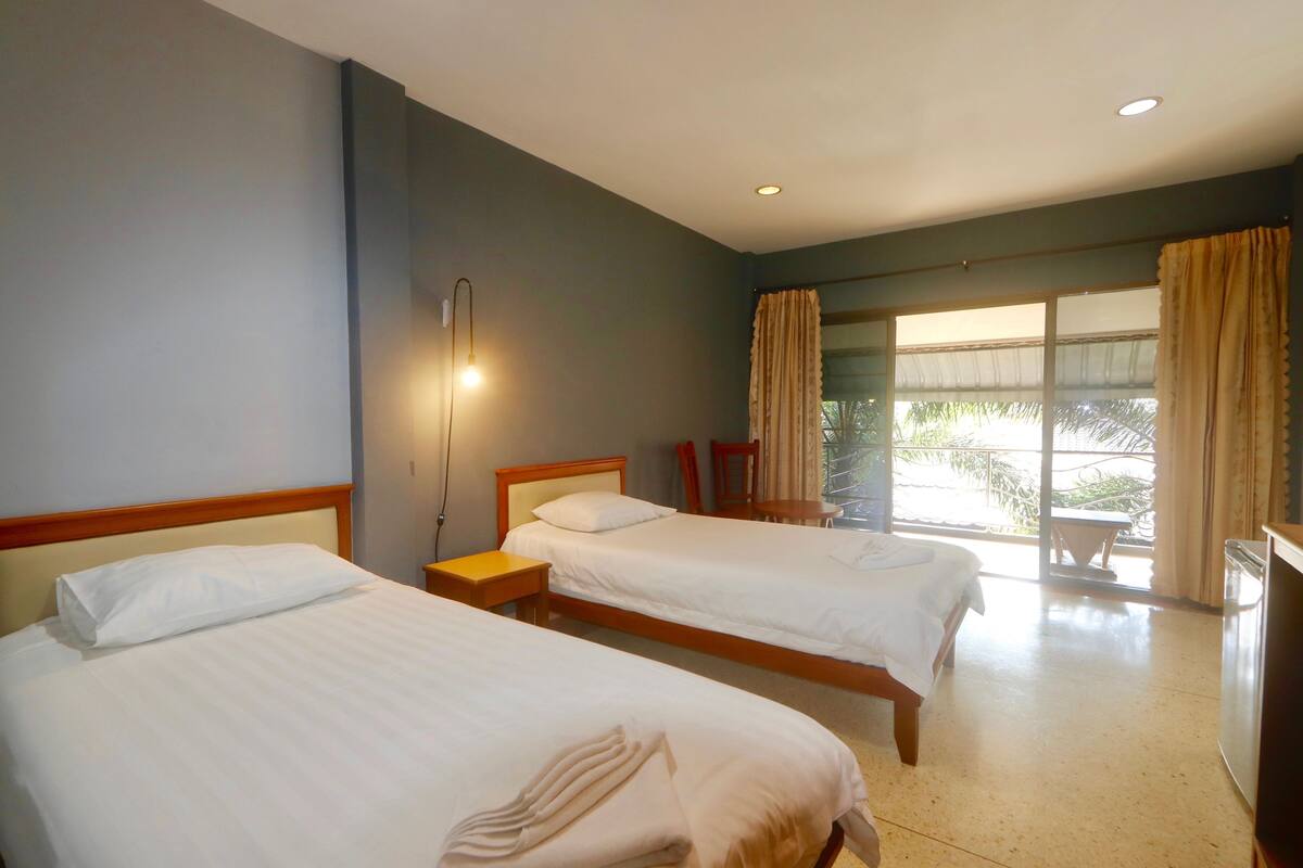 A hotel room with two beds, a nightstand, a desk, and a television.