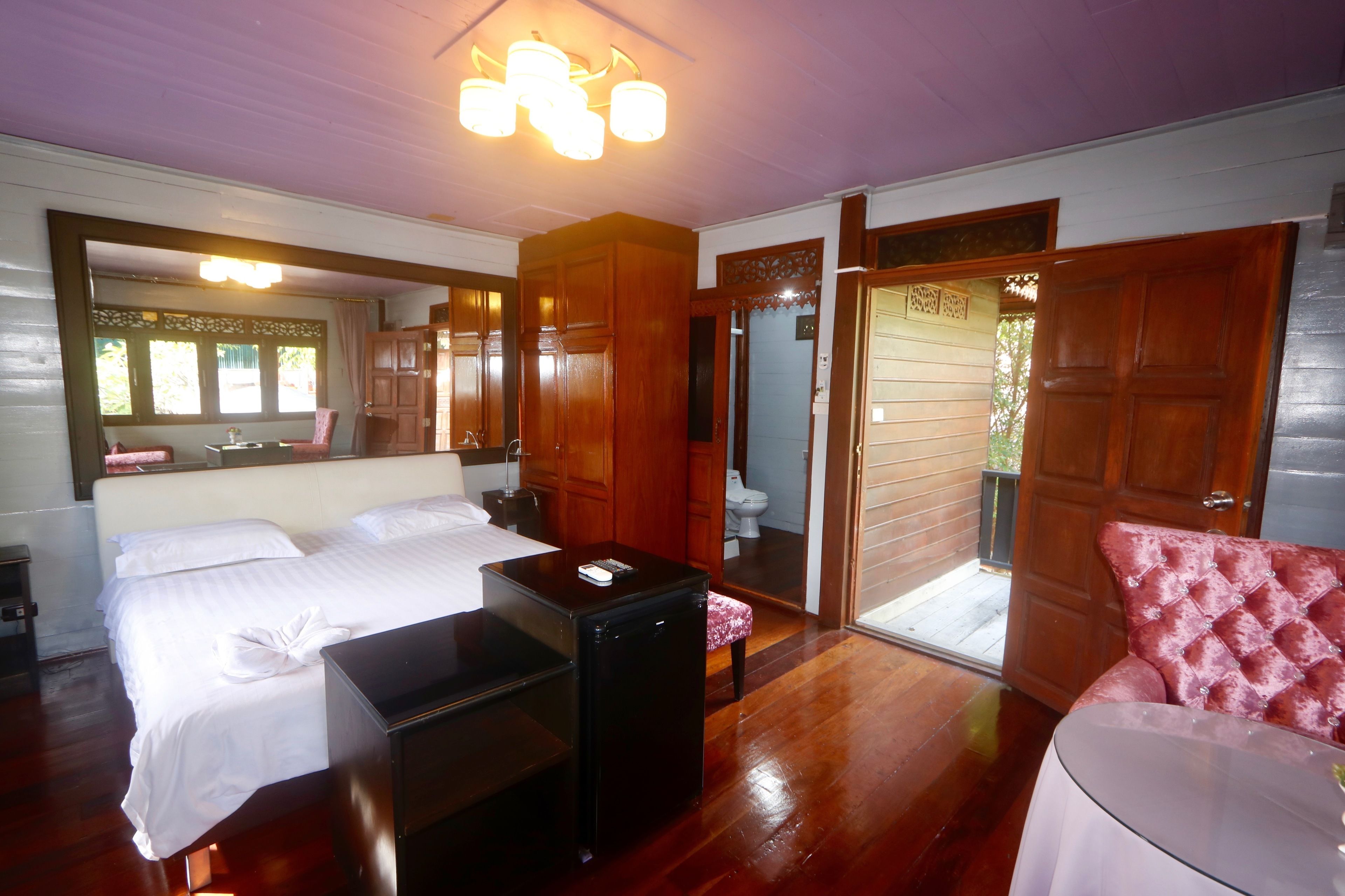 A bedroom with two beds, a small table, a mirror, and a door leading to a bathroom.