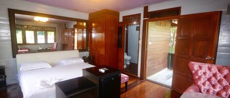 A bedroom with two beds, a small table, a mirror, and a door leading to a bathroom.