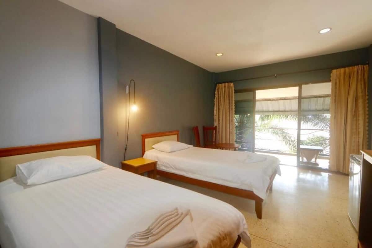 A hotel room with two beds, a desk, a chair, and a large window with curtains.