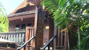 A wooden building with a staircase leading to a door, surrounded by lush greenery. - Momento Resort (Pattaya)