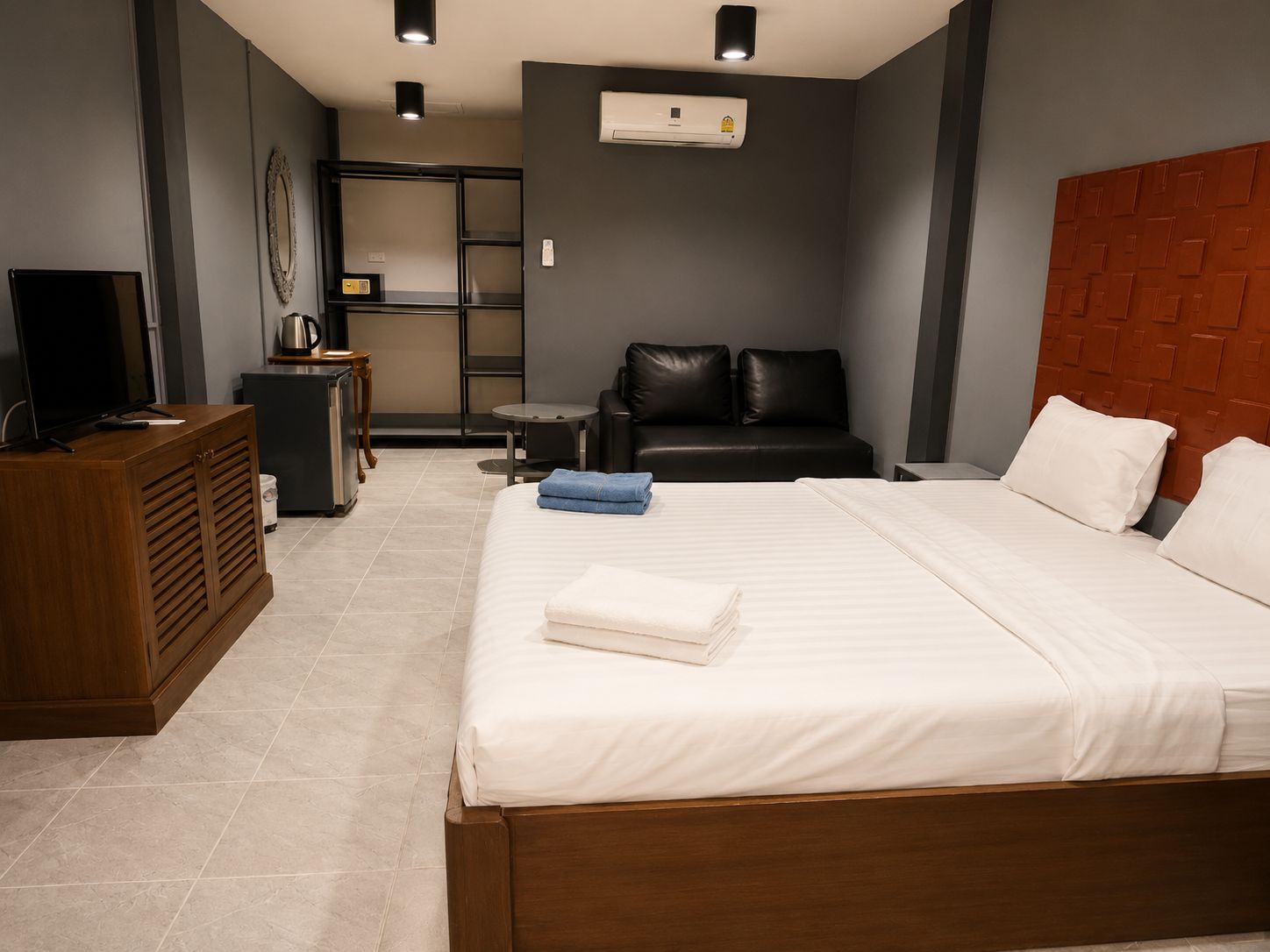 Ein Hotelzimmer mit einem Bett, einem Fernseher, einer Kaffeemaschine, einem Sofa und einer Klimaanlage.