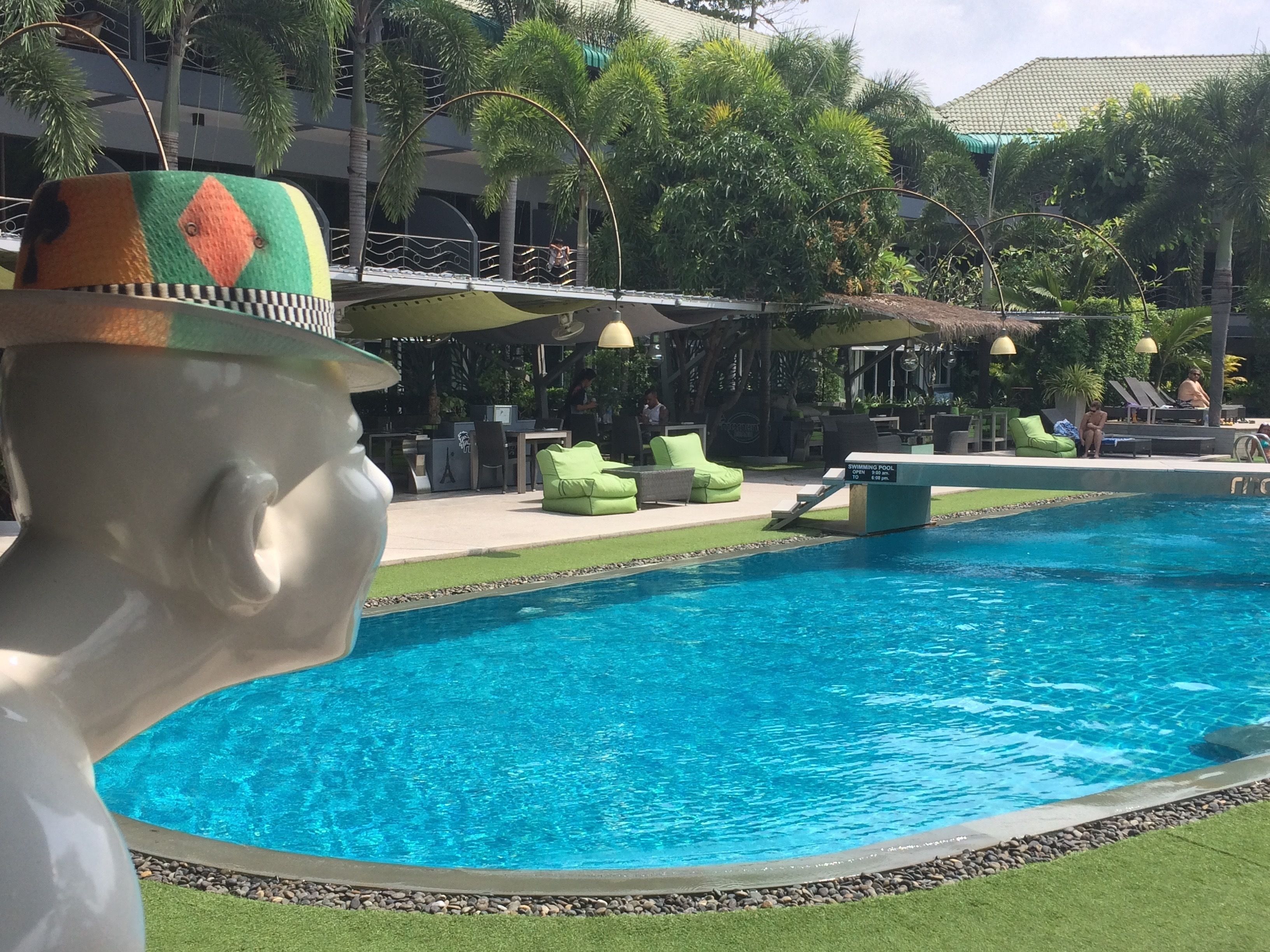 Una piscina con sillones de descanso y una estatua.
