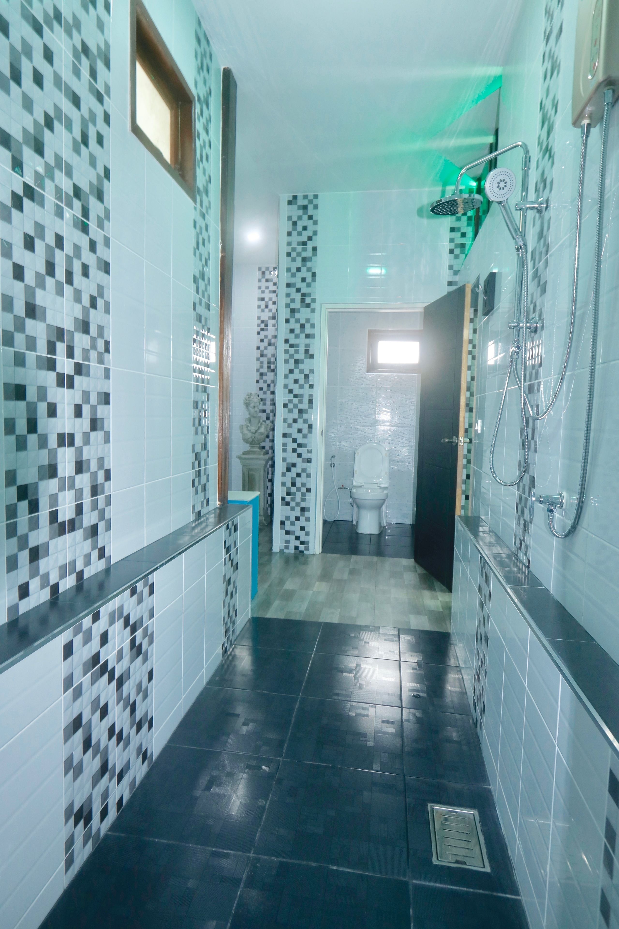 A modern bathroom with black tiled floors, a shower area, and a toilet.