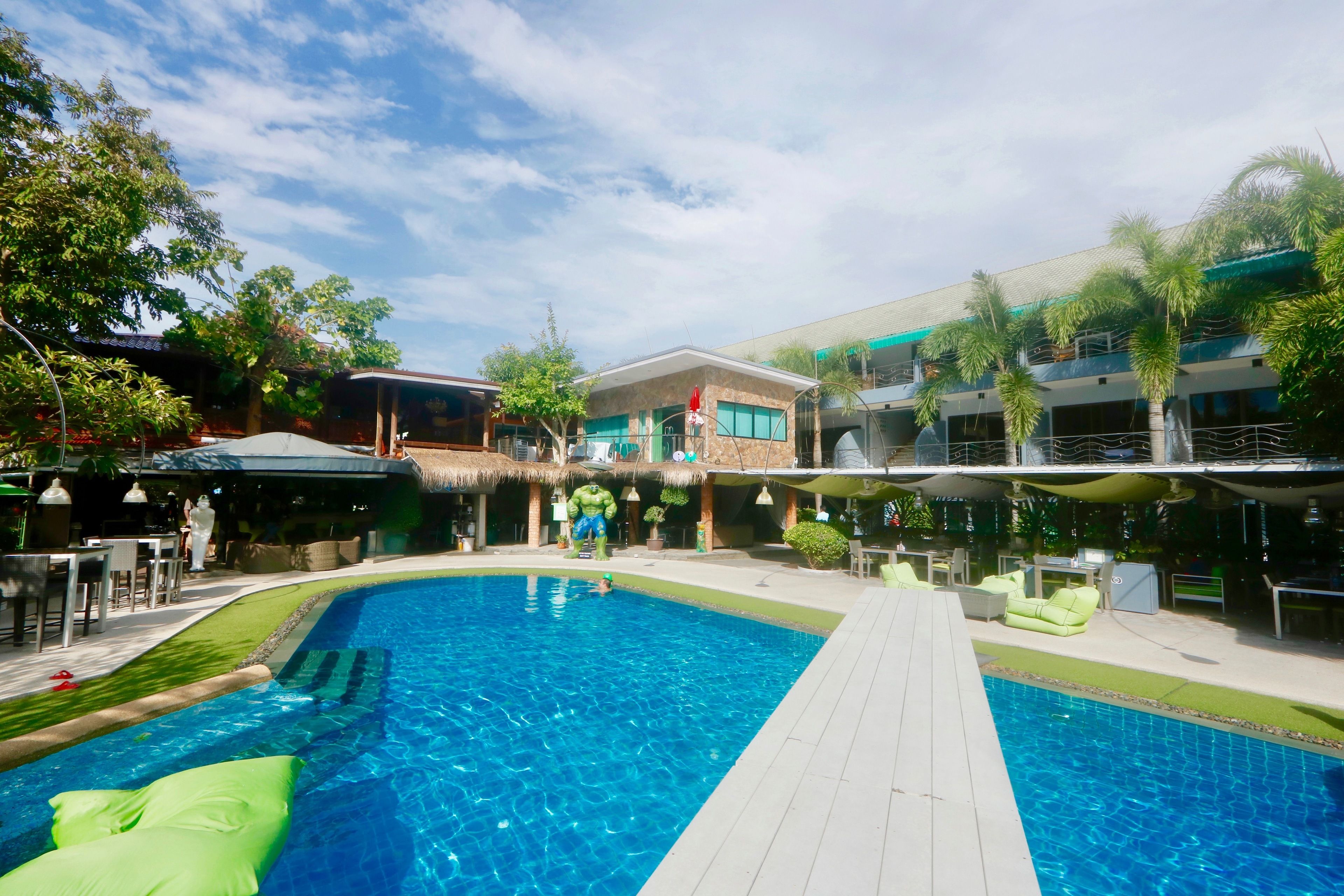 A swimming pool with a wooden deck, surrounded by lounge chairs and umbrellas.