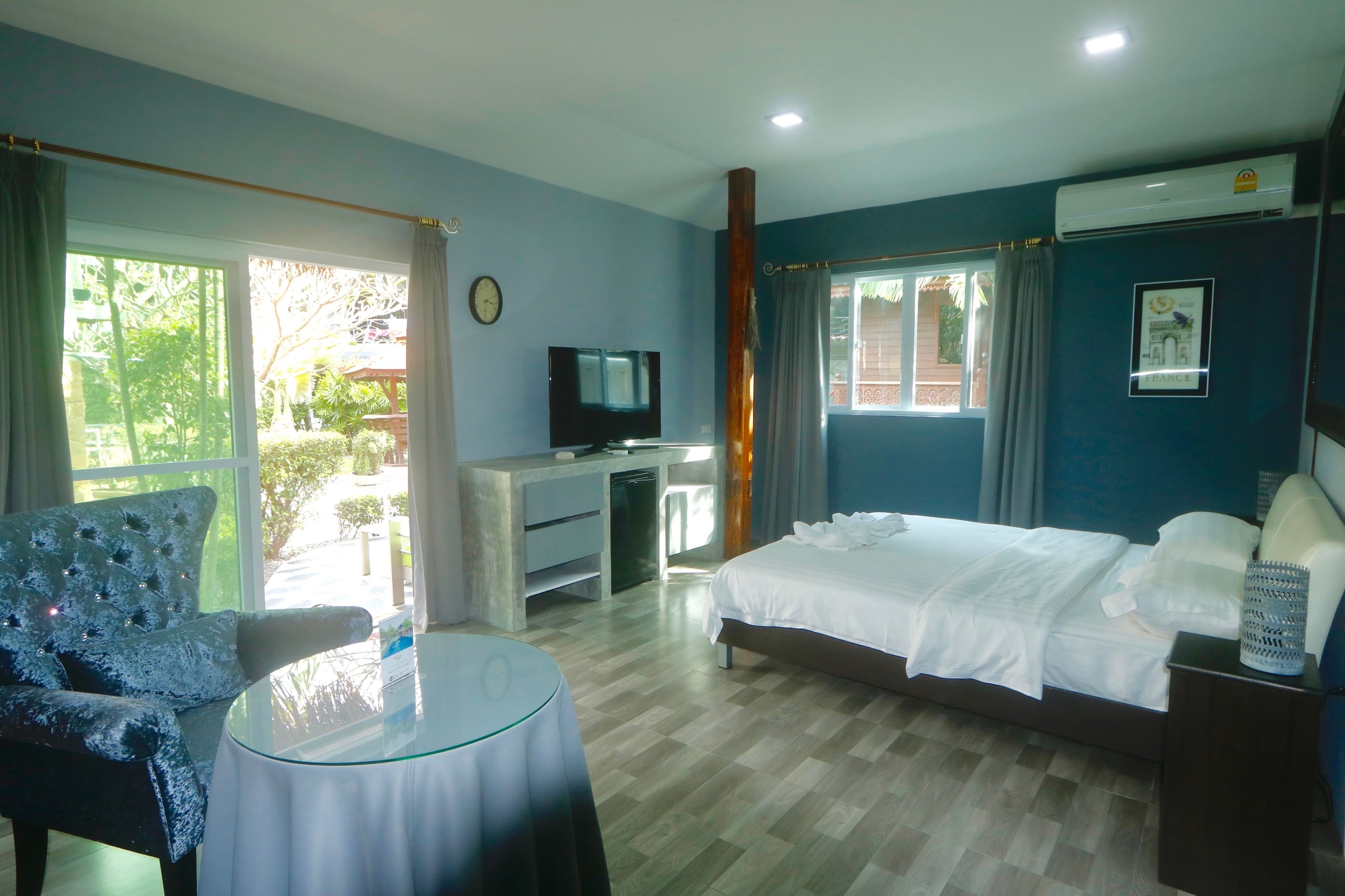 A hotel room with a bed, a desk, a chair, a TV, and a window with curtains.