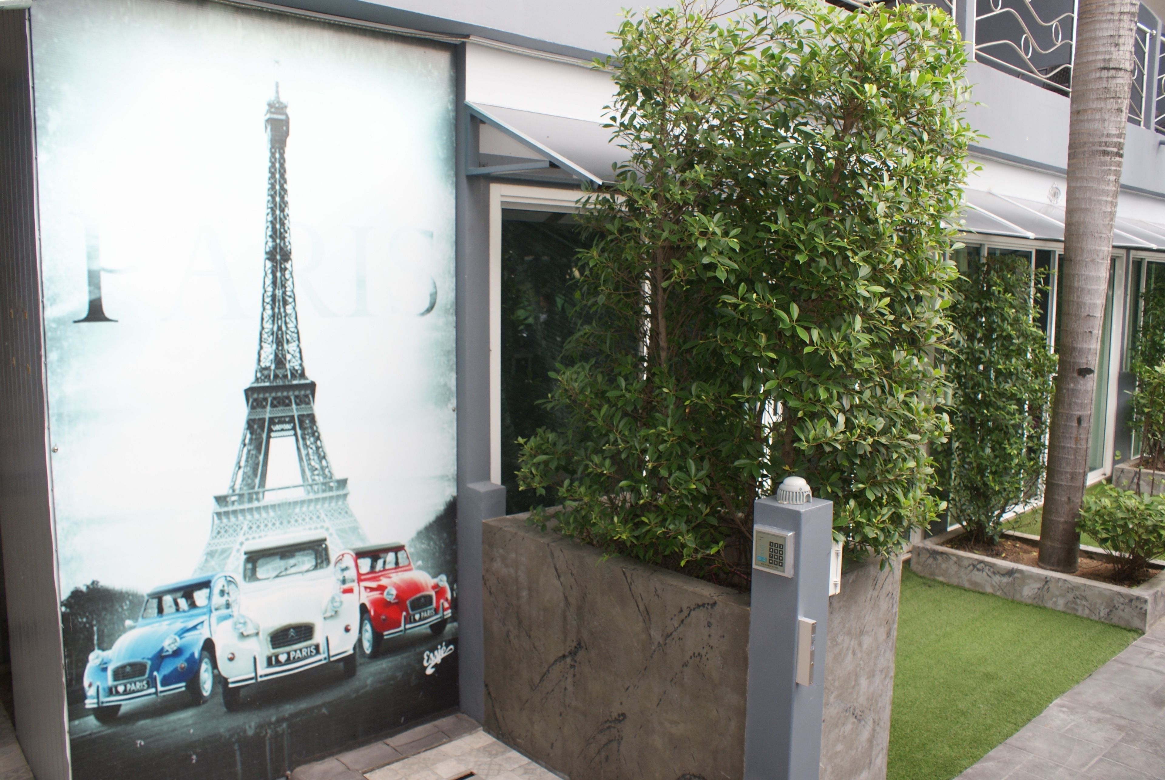 A mural of the Eiffel Tower and vintage cars on a building facade.