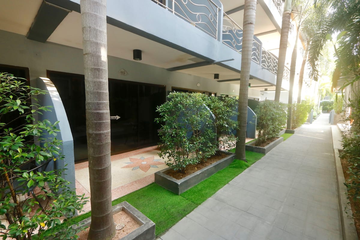 A modern building with a covered walkway, palm trees, and a flower-patterned floor.