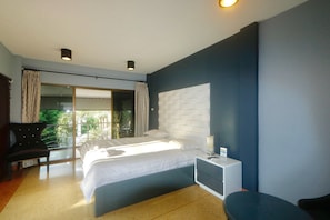 A modern bedroom with a large bed, a bedside table, a chair, and a view of the outdoors. - Momento Resort (Pattaya)