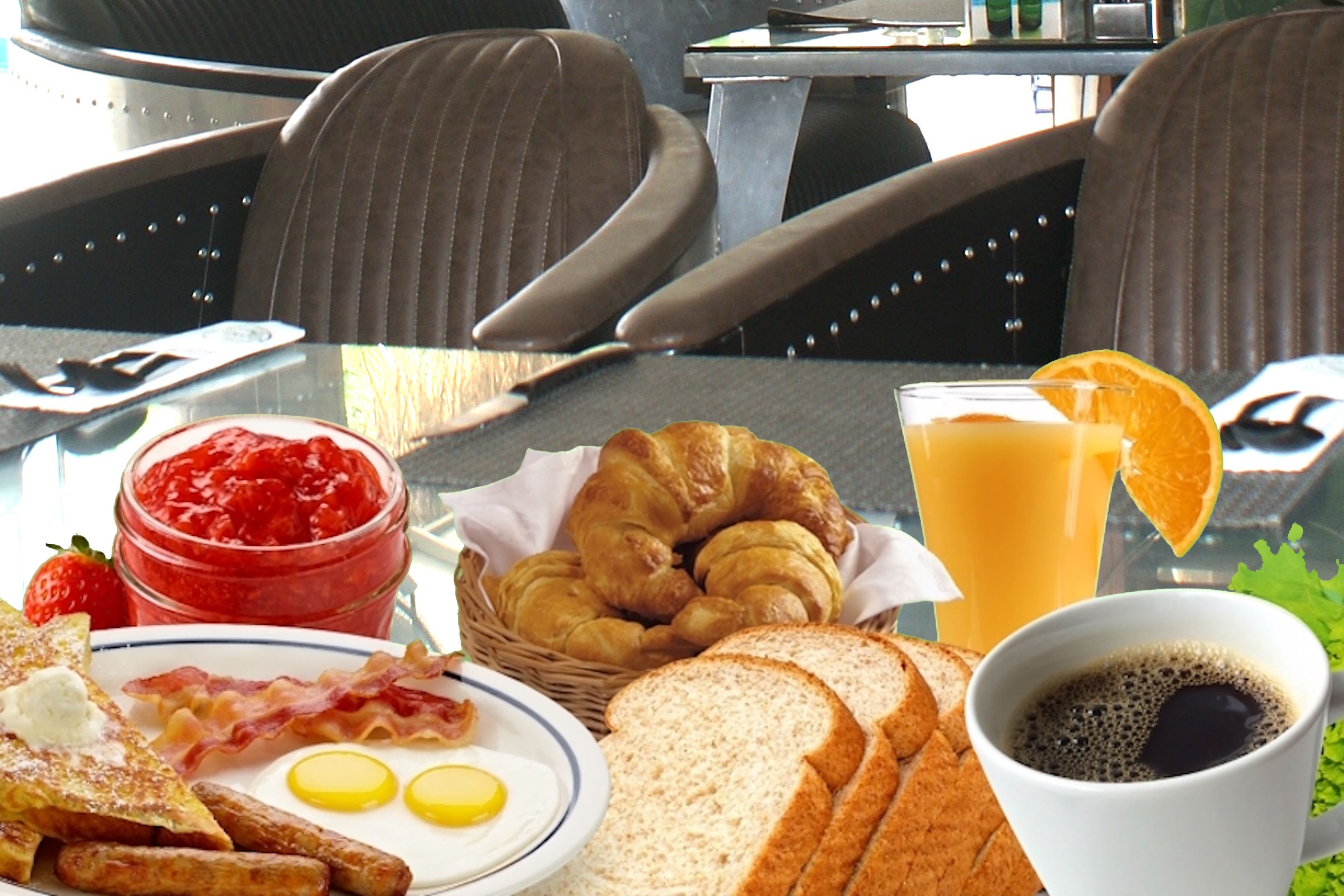 A breakfast table with croissants, toast, jam, eggs, and a glass of orange juice.