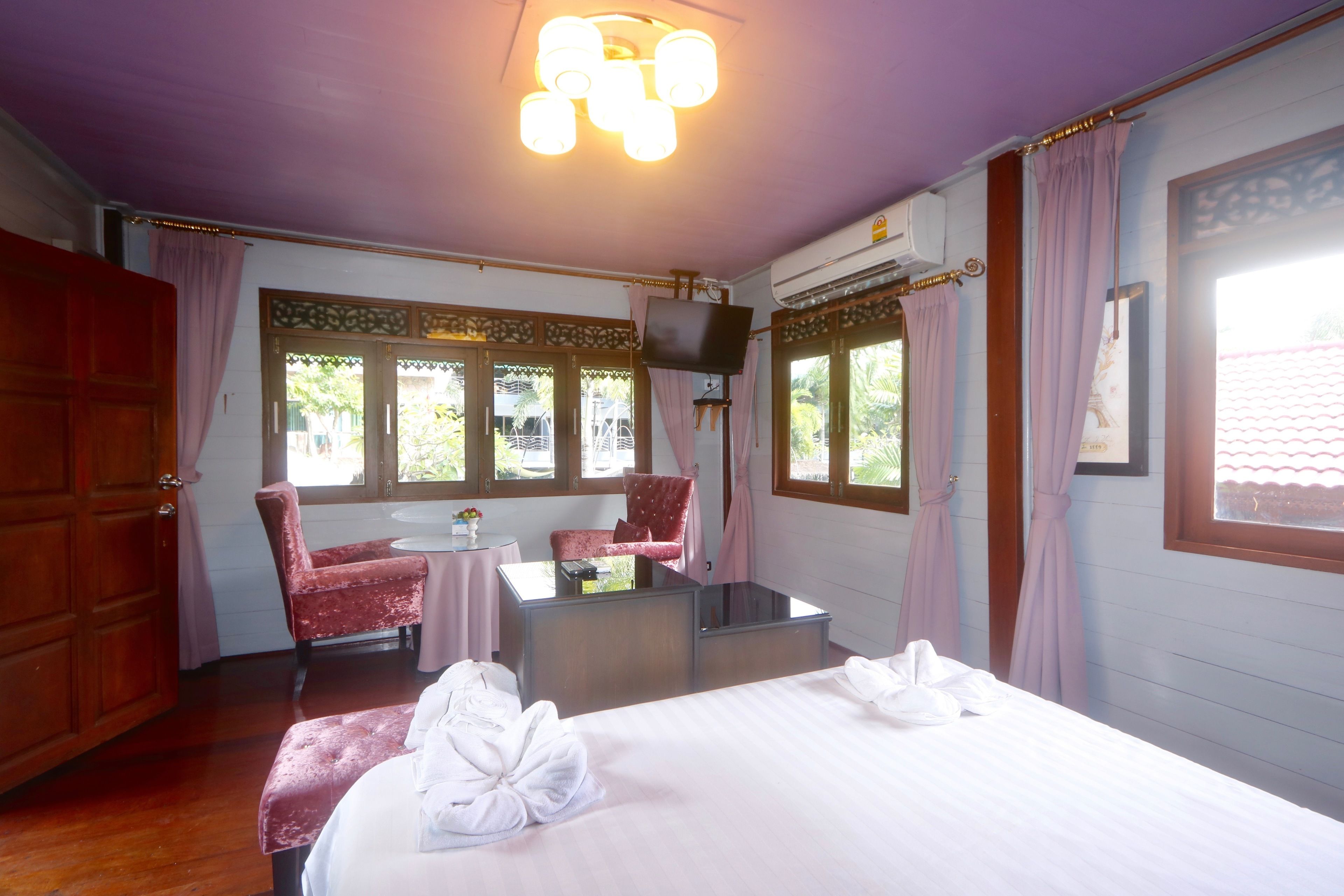 A hotel room with a bed, two chairs, a small table, and a television.