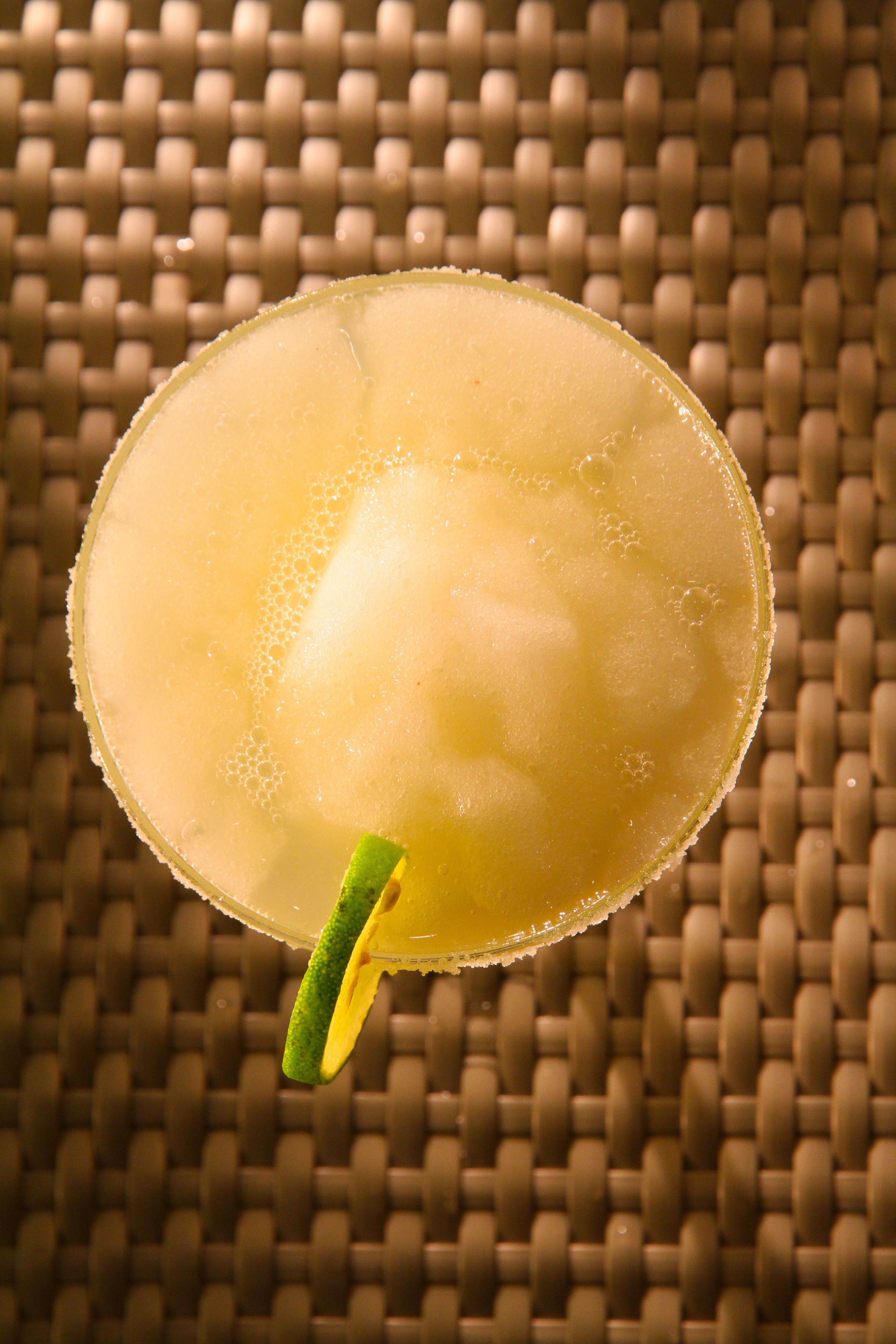 Un cocktail décoré d’une tranche de citron vert, présenté sur un tapis tissé.