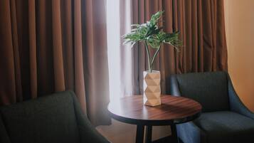 Una habitación con dos sillas, una mesita y una planta en maceta.