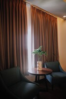 Una habitación con dos sillas, una mesita y una planta en maceta.