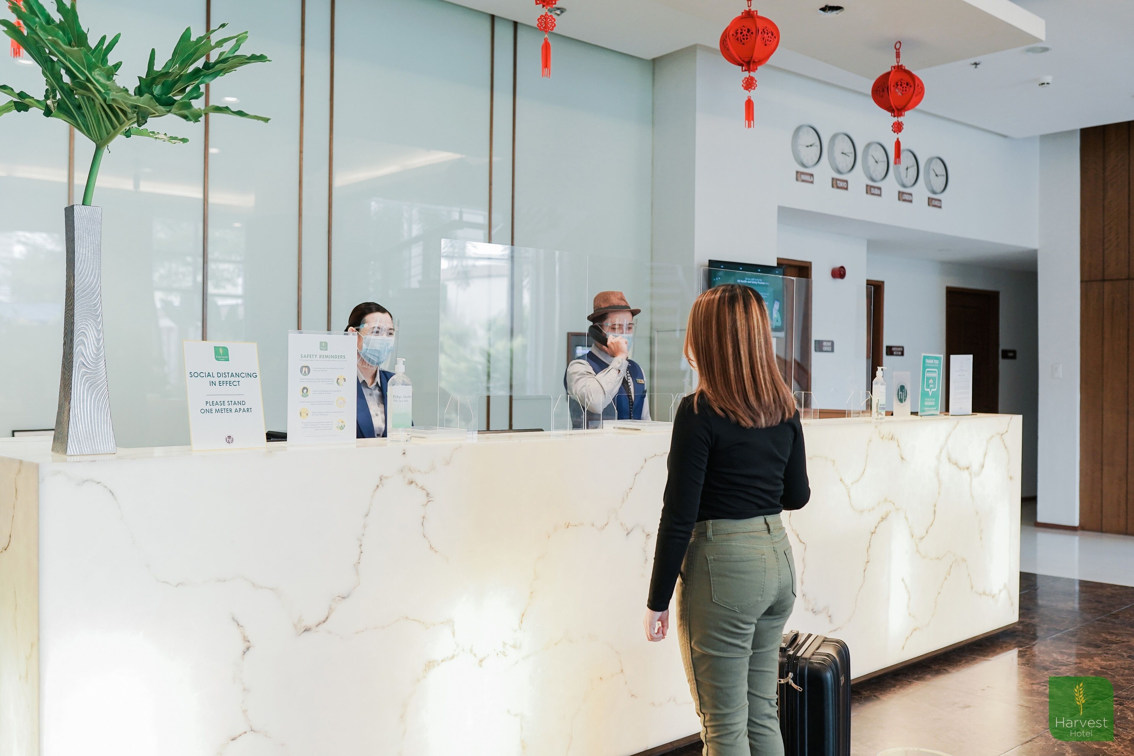 A hotel reception desk with a marble counter, a potted plant, and red lanterns.