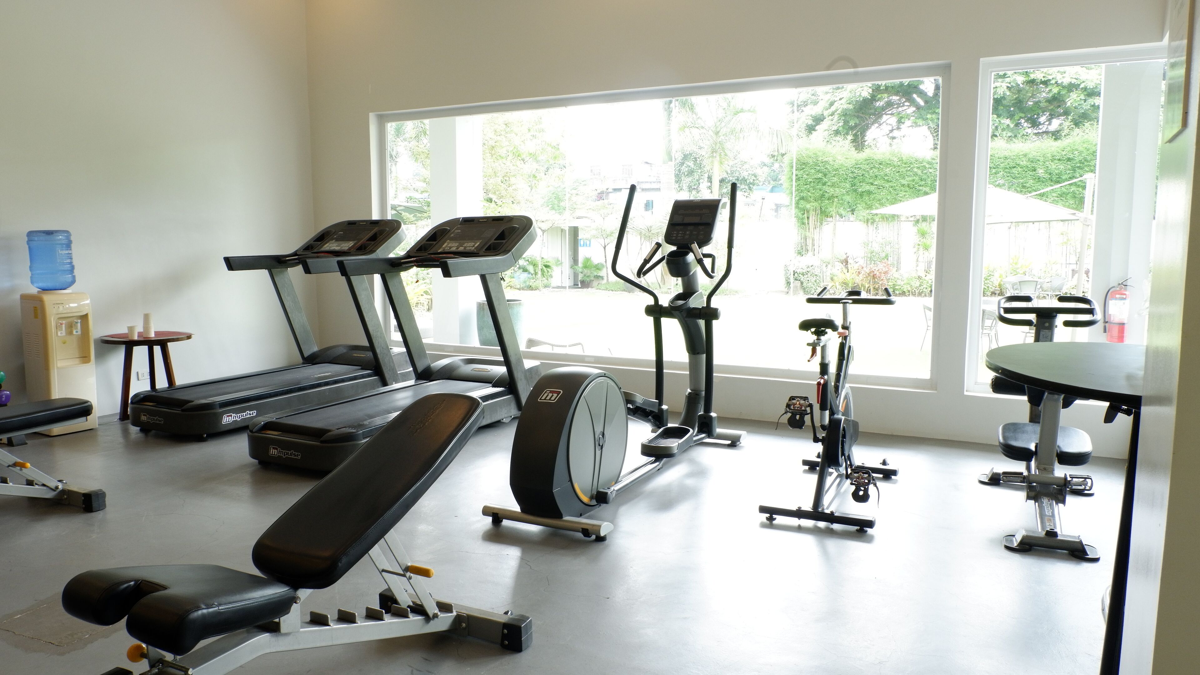 A gym with treadmills, an elliptical, a bench press, and a water dispenser.