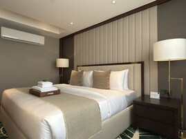Habitación de hotel con una cama grande, una mesita de noche, una lámpara y un equipo de aire acondicionado en la pared.