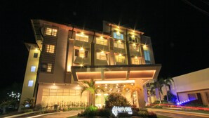 A multi-story hotel with a modern design, featuring a well-lit entrance and a landscaped garden area.