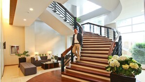 A spacious living area with a curved staircase, a sofa set, and a coffee table.