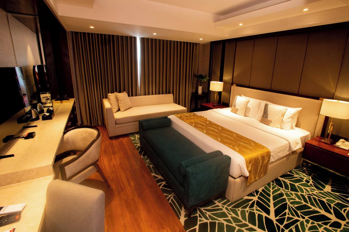 A hotel room with a bed, a sofa, a desk, and a chair.