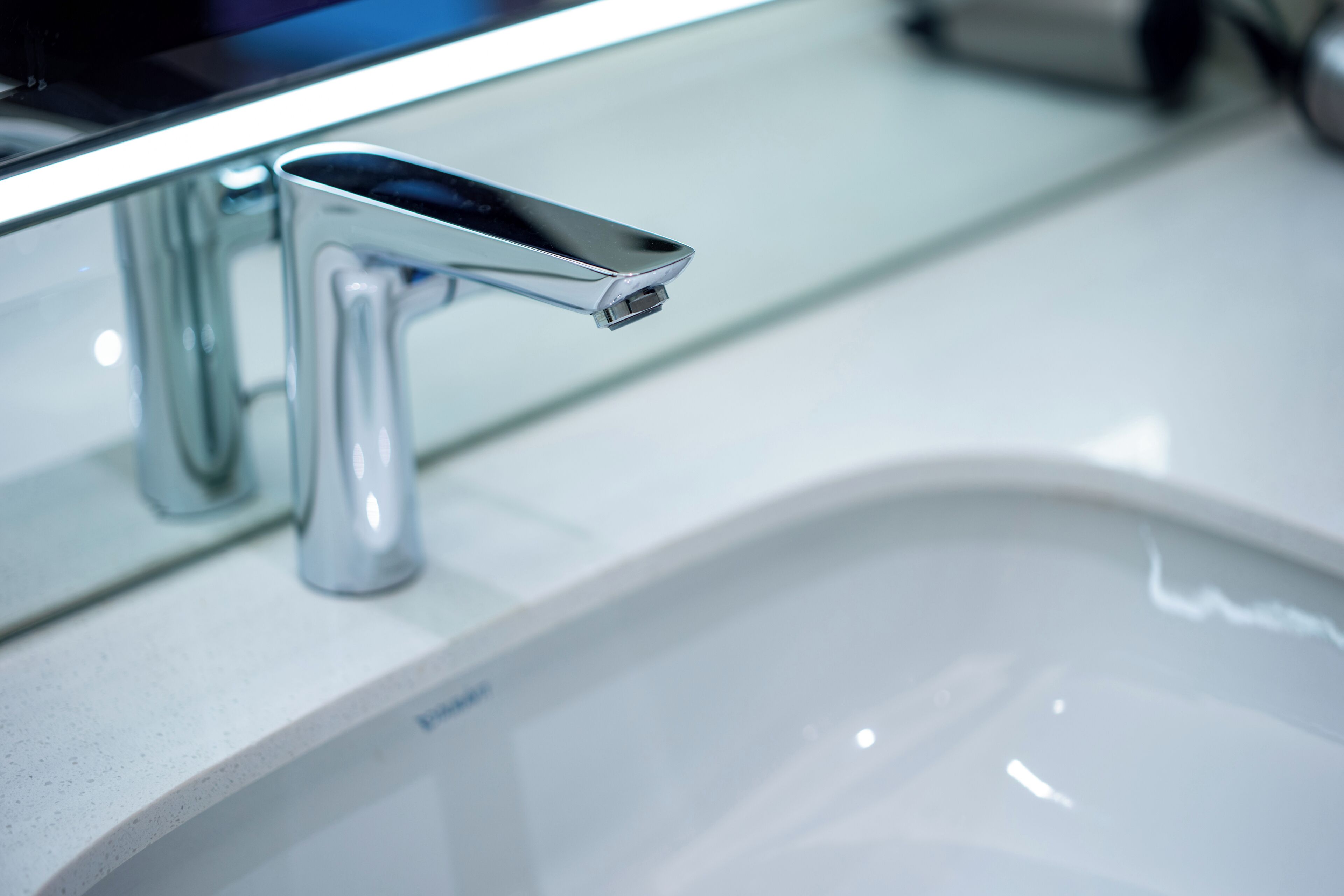 A modern bathroom with a chrome faucet and a white sink.