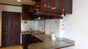 Une cuisine avec des meubles de couleur bois foncé, un plan de travail en granit, un évier en acier inoxydable et un luminaire suspendu.