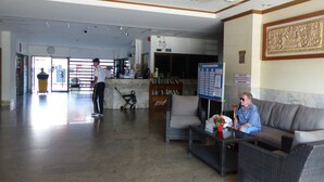 Un hall d’entrée spacieux avec un comptoir de réception, un espace d’attente doté d’un canapé et de fauteuils, et une poubelle bien visible.