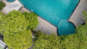 An aerial view of a rectangular swimming pool with a small circular hot tub, surrounded by a paved deck and greenery. - PRS Hotel by Sojourn (Pattaya)