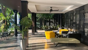 A modern indoor area with a ceiling fan, yellow and black seating, and a large potted plant. - PRS Hotel by Sojourn (Pattaya)