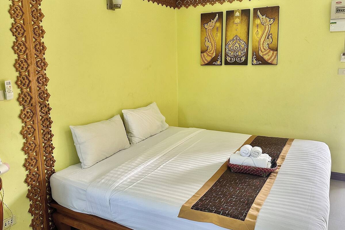 A neatly made bed with white linens, a decorative headboard, and a brown and white patterned bed runner.