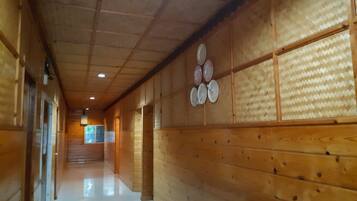 A wooden hallway with a tiled ceiling and a wall with a patterned design.