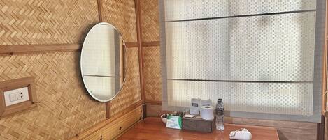 A wooden-paneled bathroom with a wooden vanity, a mirror, a towel, and a small trash bin.