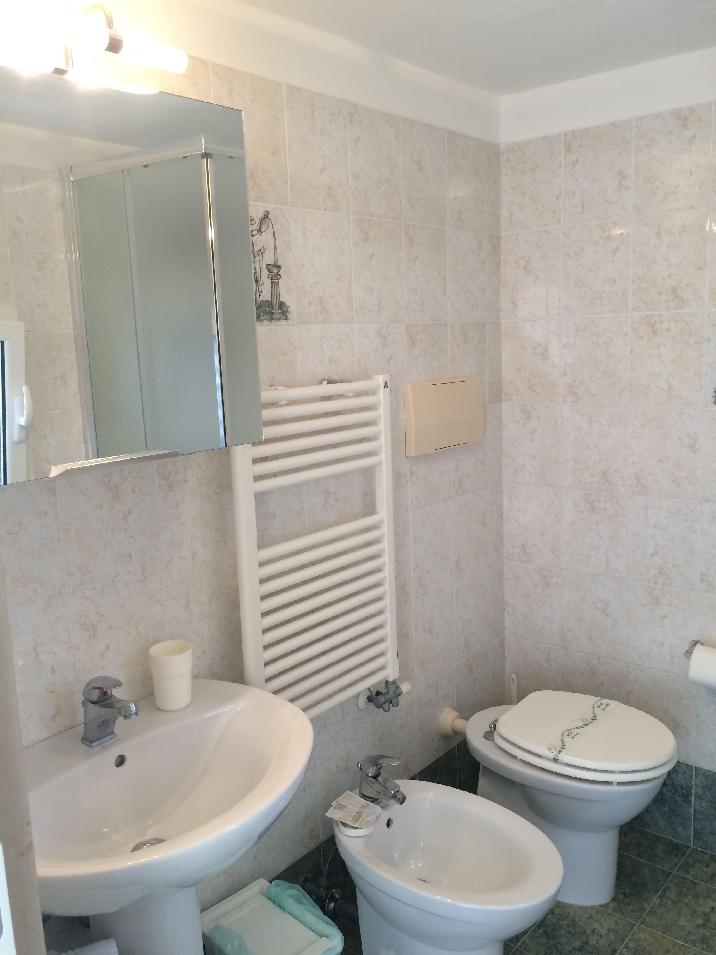 A bathroom with a sink, bidet, toilet, and a towel rack.
