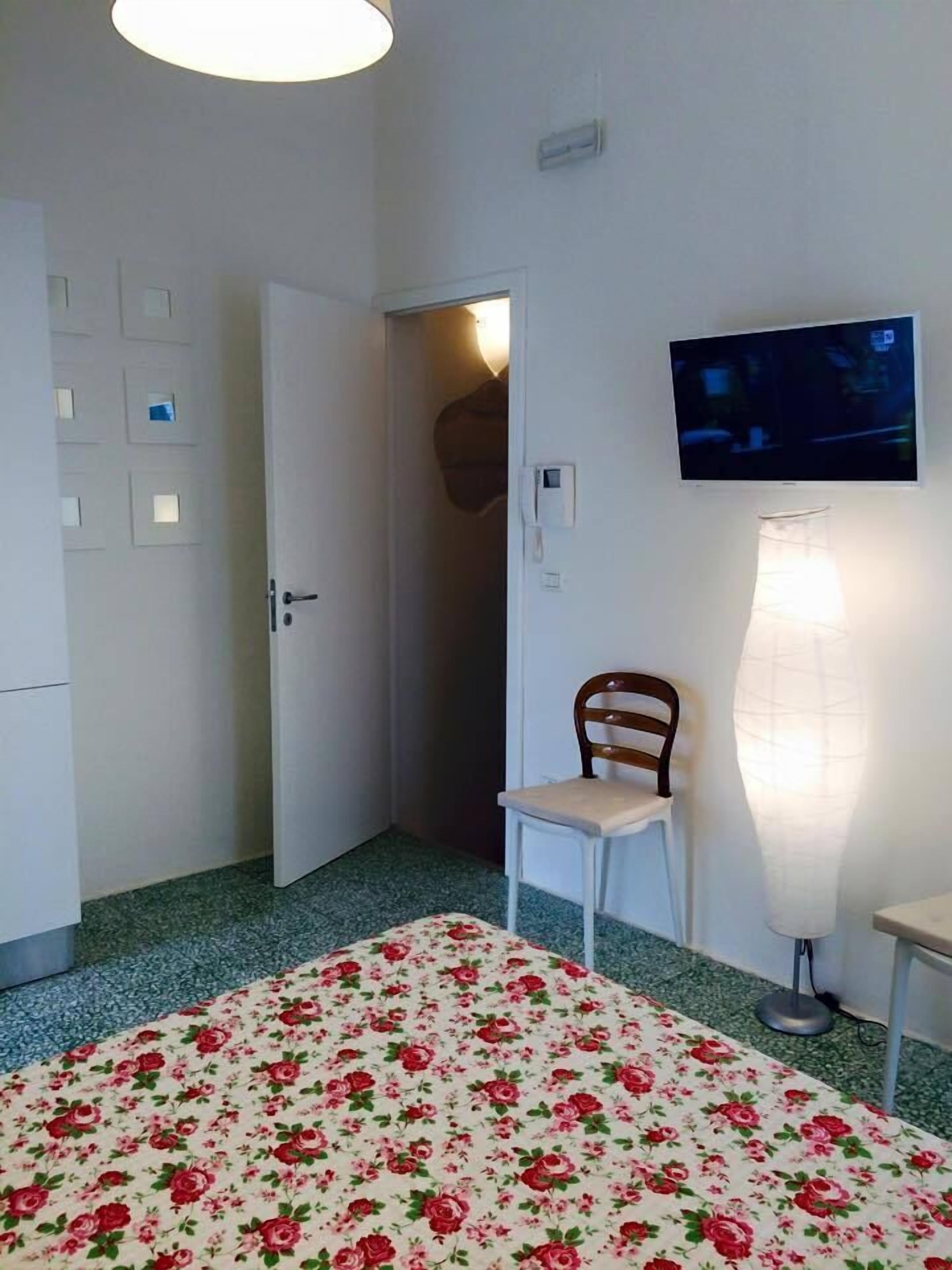 A room with a bed, a chair, a television, and a door.