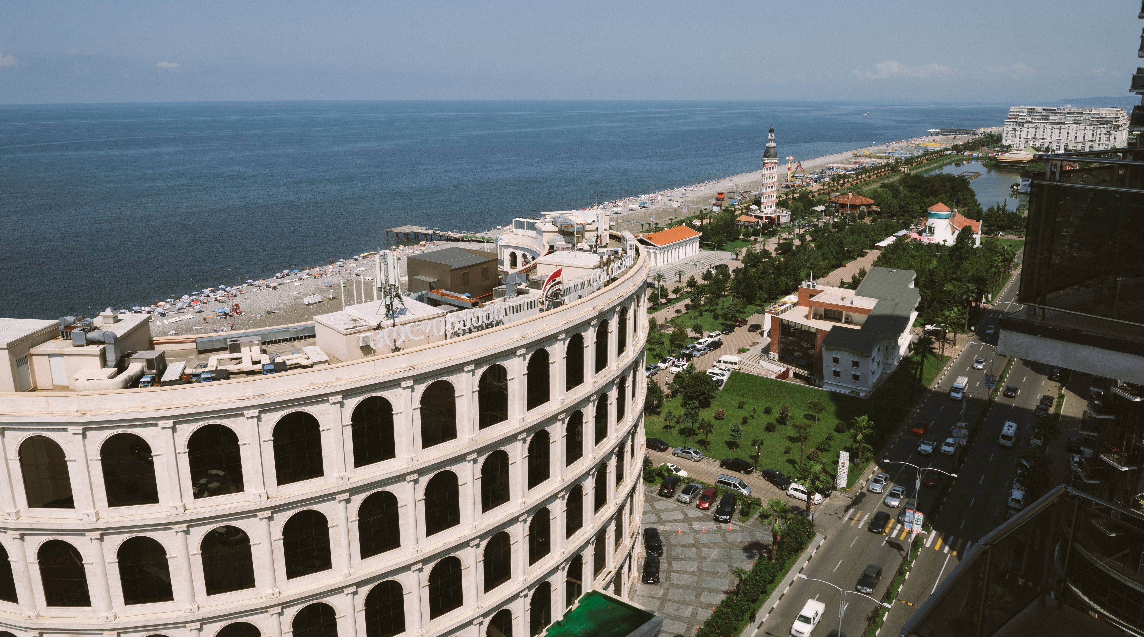 A large, historic building with multiple arches and a dome, overlooking a coastal area with a beach and a body of water.