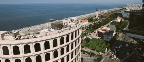 A large, historic building with multiple arches and a dome, overlooking a coastal area with a beach and a body of water.