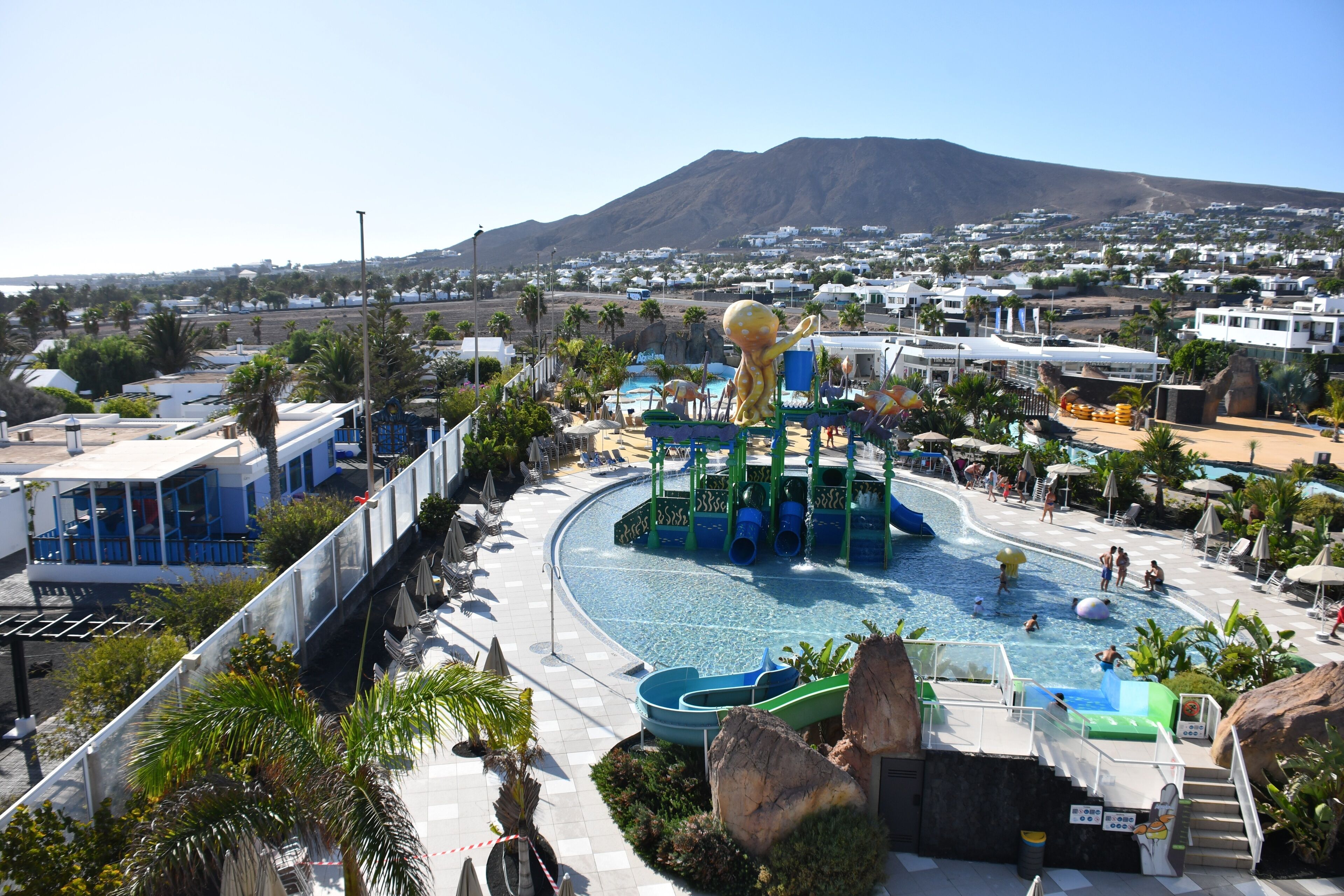 A resort with a swimming pool, water slides, and a view of a mountain.