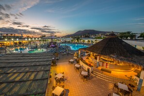 A resort pool area with lounge chairs and umbrellas, a bar, and a view of a mountain. - Relaxia Lanzasur- All Inclusive (Yaiza)